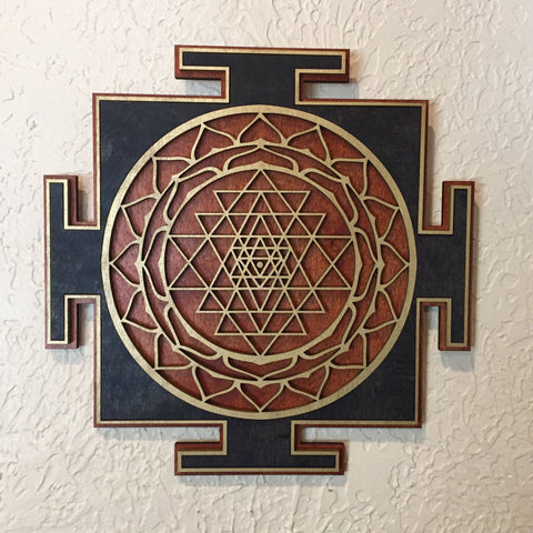 Black, gold, and red Sri Yantra centered on a light wall