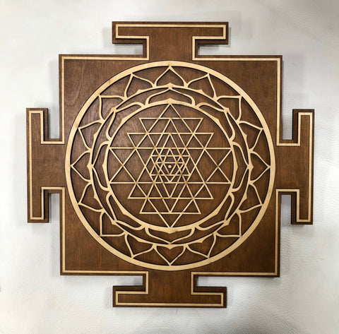 Brown and natural-stained Sri Yantra centered against a light wall
