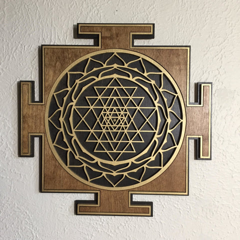 Brown, black, and gold Sri Yantra centered on a light wall