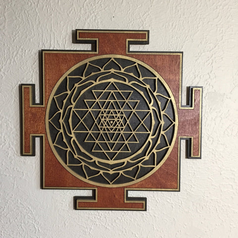 Red, black, and gold Sri Yantra centered on a light wall